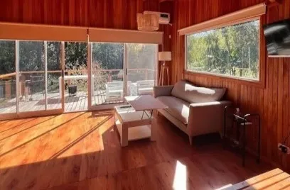 La cabaña por dentro, con piso de madera y ventanales