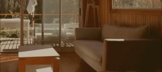 El living de la cabaña, con el sillón y el ventanal al bosque